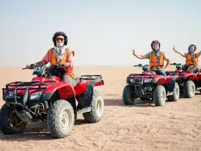 Adventurers riding quad bikes at sunset on a desert trail during a Sunset Quad Safari Trip Marsa Alam