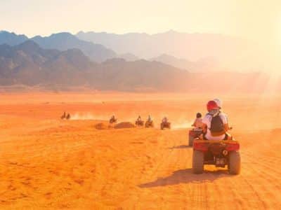 Adventurers riding quad bikes at sunset on a desert trail during a Sunset Quad Safari Trip Marsa Alam